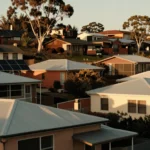 Rooftops of a hillside Albury neighbourhood at golden hour with solar panels and gum canopy